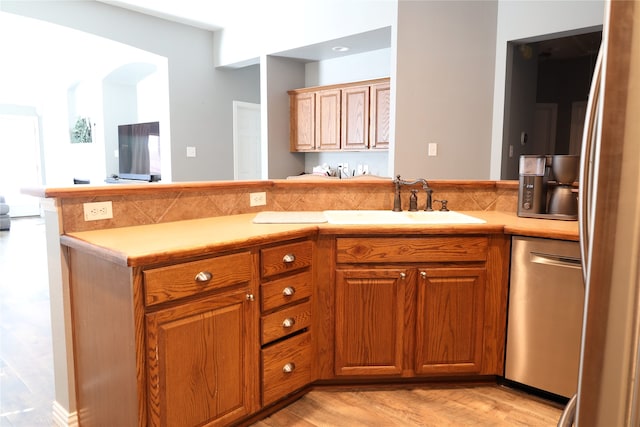 kitchen featuring kitchen peninsula, light wood-type flooring, fridge, dishwasher, and sink