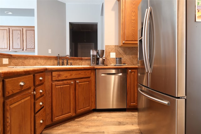 kitchen featuring light hardwood / wood-style floors, appliances with stainless steel finishes, sink, and backsplash