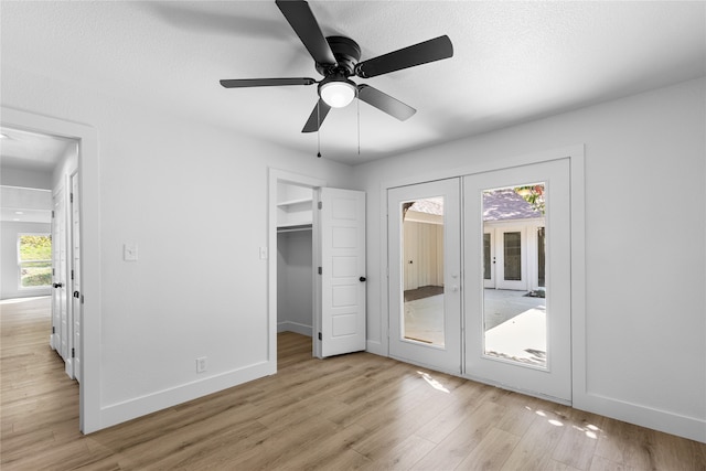 unfurnished bedroom with french doors, access to exterior, light hardwood / wood-style flooring, a spacious closet, and ceiling fan