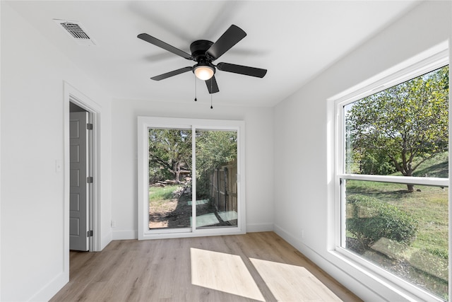 empty room featuring ceiling fan, a wealth of natural light, and light wood-type flooring