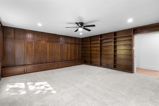 carpeted spare room featuring built in shelves and ceiling fan