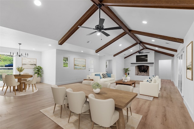 dining room with light hardwood / wood-style flooring, lofted ceiling with beams, ceiling fan with notable chandelier, and a brick fireplace