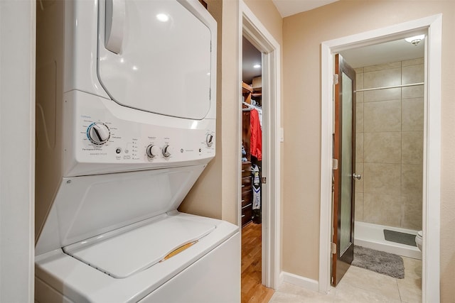 laundry room with stacked washer / dryer and light tile patterned flooring