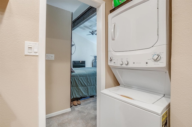 laundry room featuring light carpet, stacked washer and dryer, and ceiling fan