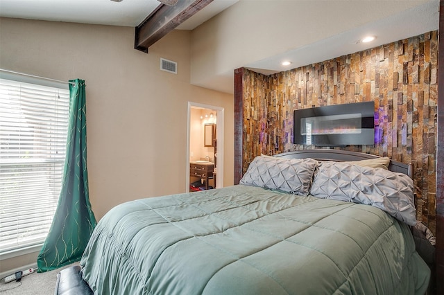 bedroom with beamed ceiling, carpet, and ensuite bathroom