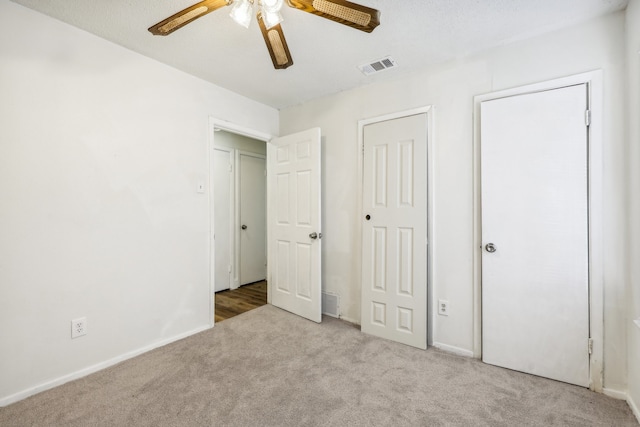 unfurnished bedroom featuring ceiling fan, light colored carpet, and a textured ceiling