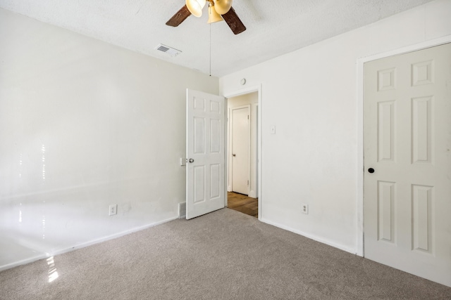 unfurnished bedroom with a textured ceiling, carpet floors, and ceiling fan