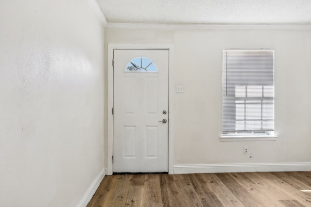 entrance foyer with wood-type flooring, a textured ceiling, and crown molding