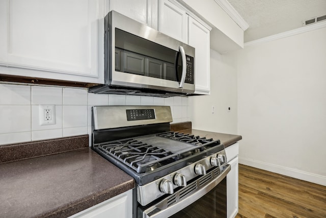 kitchen featuring a textured ceiling, stainless steel appliances, white cabinetry, and dark hardwood / wood-style floors