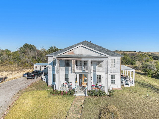 view of front facade with a front yard and a balcony