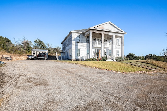 greek revival inspired property with a front yard and a balcony