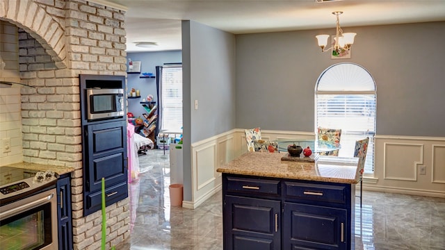 kitchen featuring appliances with stainless steel finishes, blue cabinets, pendant lighting, light stone counters, and a chandelier