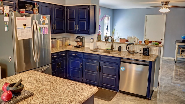 kitchen featuring appliances with stainless steel finishes, sink, blue cabinets, ceiling fan, and decorative backsplash