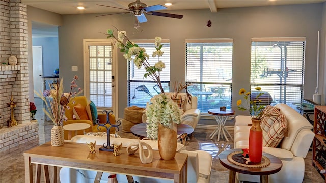 interior space with a brick fireplace, beam ceiling, and ceiling fan