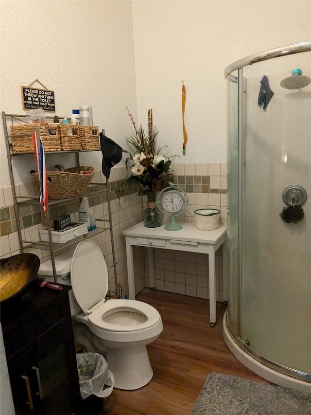 bathroom with toilet, tile walls, a shower with shower door, and hardwood / wood-style floors