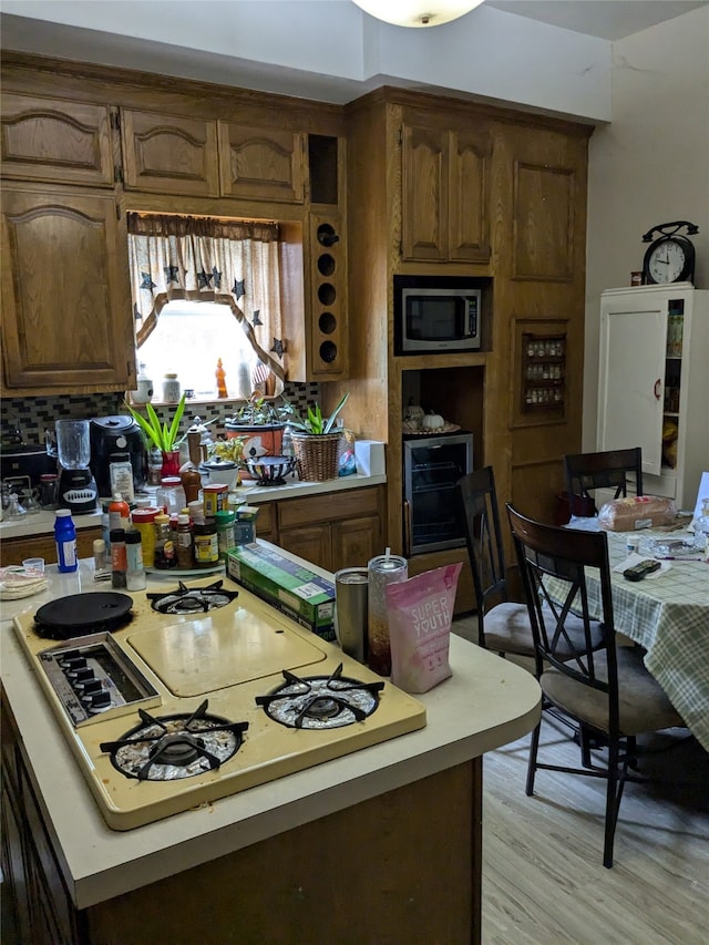 kitchen with wine cooler, light hardwood / wood-style flooring, white gas cooktop, and backsplash