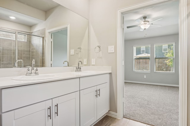 bathroom with ceiling fan, a sink, a tile shower, and double vanity