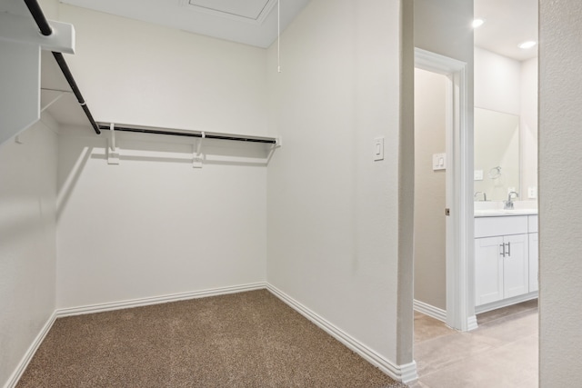 walk in closet with light carpet and a sink