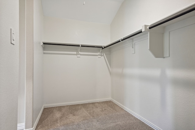 walk in closet with light colored carpet and vaulted ceiling