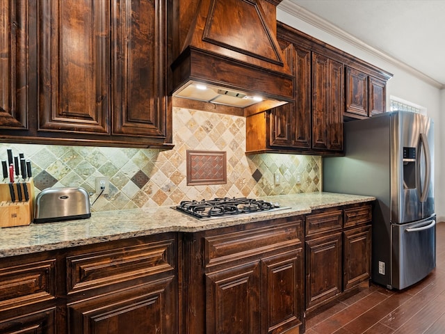 kitchen with appliances with stainless steel finishes, backsplash, dark hardwood / wood-style flooring, crown molding, and premium range hood