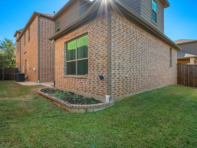 view of side of property featuring central air condition unit and a lawn