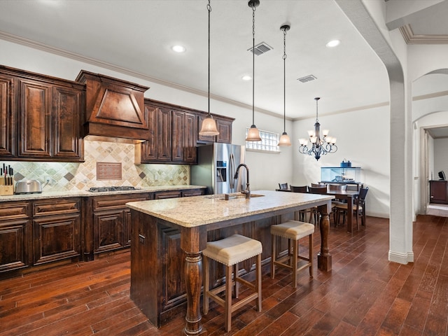 kitchen with stainless steel appliances, dark hardwood / wood-style floors, pendant lighting, and a center island with sink