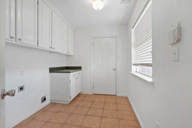 laundry room featuring hookup for an electric dryer, light tile patterned flooring, and cabinets