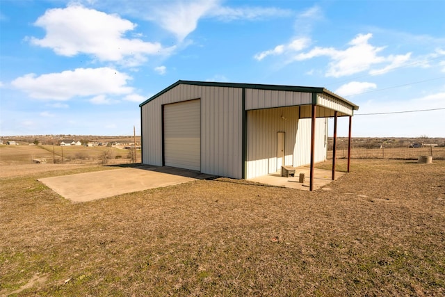 view of outbuilding featuring a lawn, a rural view, and a garage