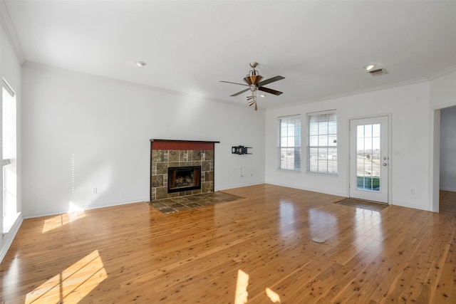 unfurnished living room with crown molding, light wood-type flooring, a fireplace, and ceiling fan