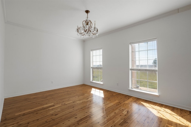 spare room featuring ornamental molding, hardwood / wood-style floors, and an inviting chandelier