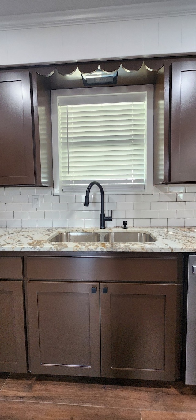 kitchen featuring dark wood-type flooring, dark brown cabinets, backsplash, ornamental molding, and sink