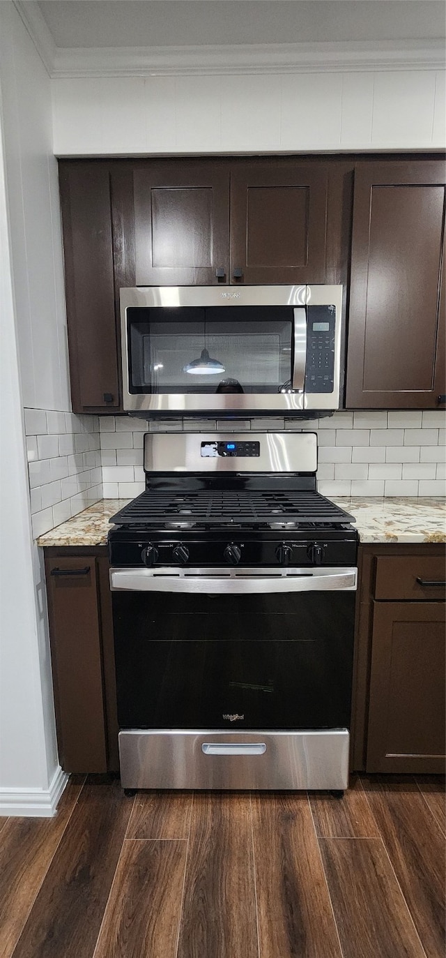 kitchen featuring appliances with stainless steel finishes, dark brown cabinetry, light stone counters, and dark hardwood / wood-style flooring