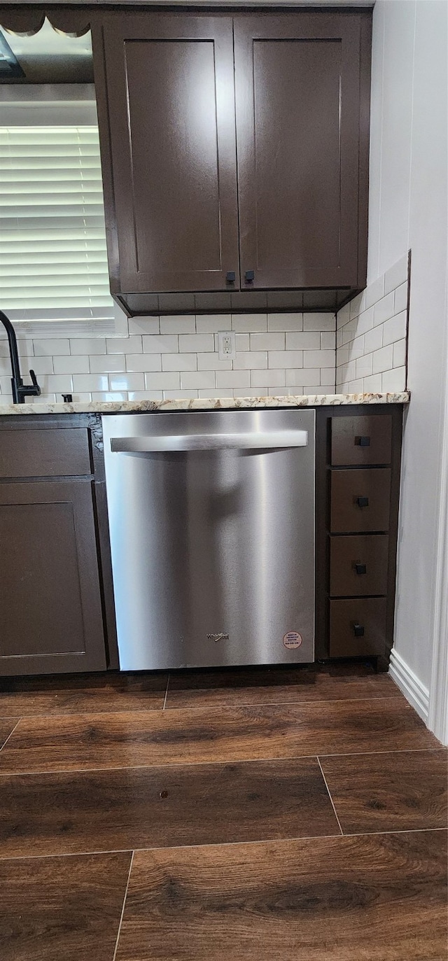 kitchen featuring tasteful backsplash, stainless steel dishwasher, dark wood-type flooring, dark brown cabinetry, and light stone counters