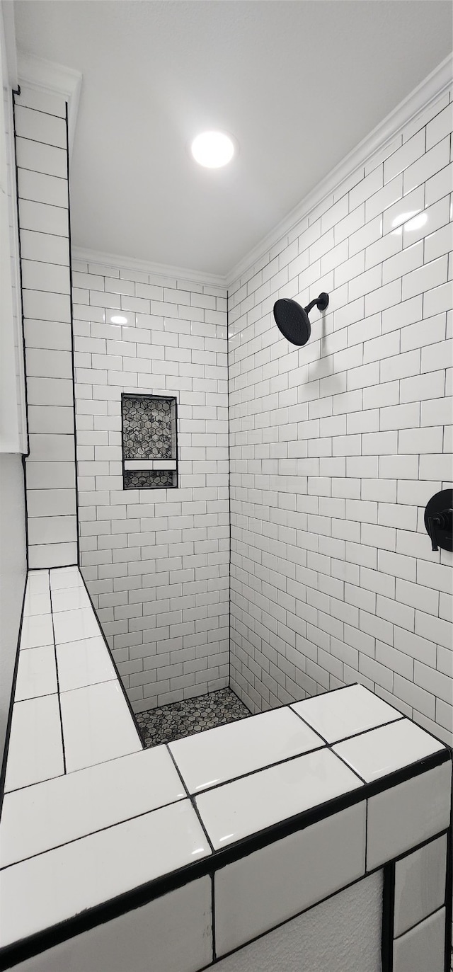 bathroom with a tile shower and crown molding