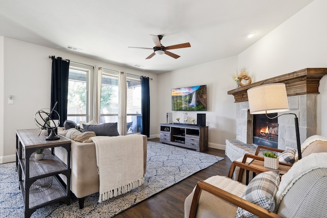 living room featuring ceiling fan, a tile fireplace, and dark hardwood / wood-style flooring