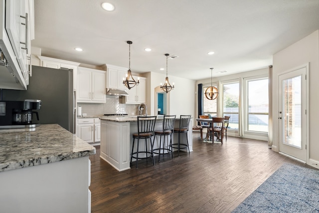 kitchen with white cabinetry, decorative light fixtures, and a kitchen island with sink