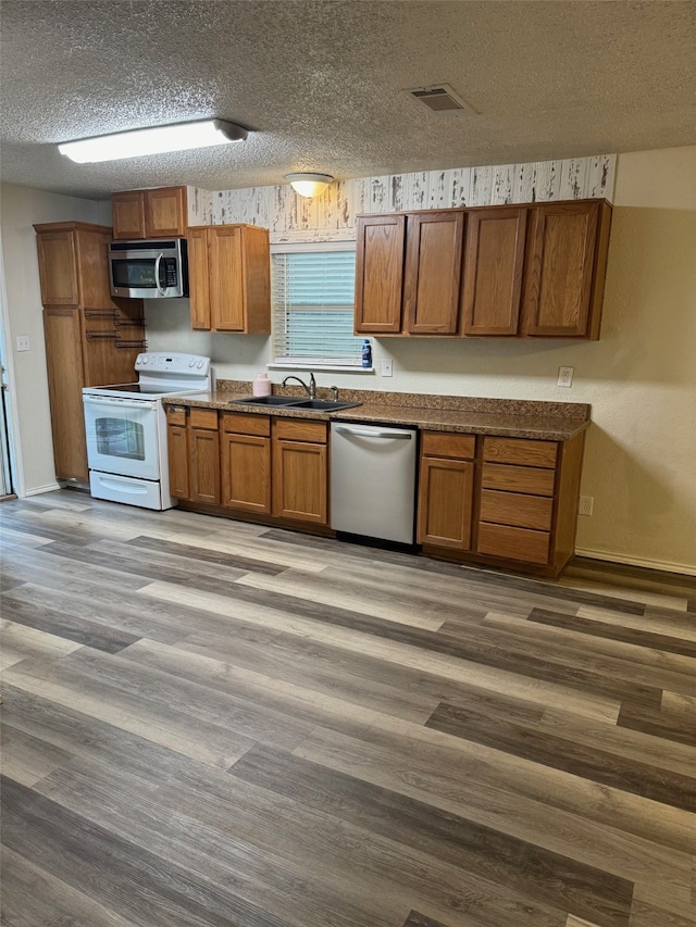 kitchen featuring sink, a textured ceiling, stainless steel appliances, and hardwood / wood-style flooring