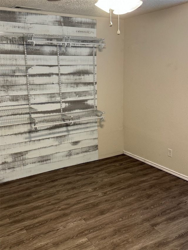 empty room featuring a textured ceiling and dark hardwood / wood-style flooring