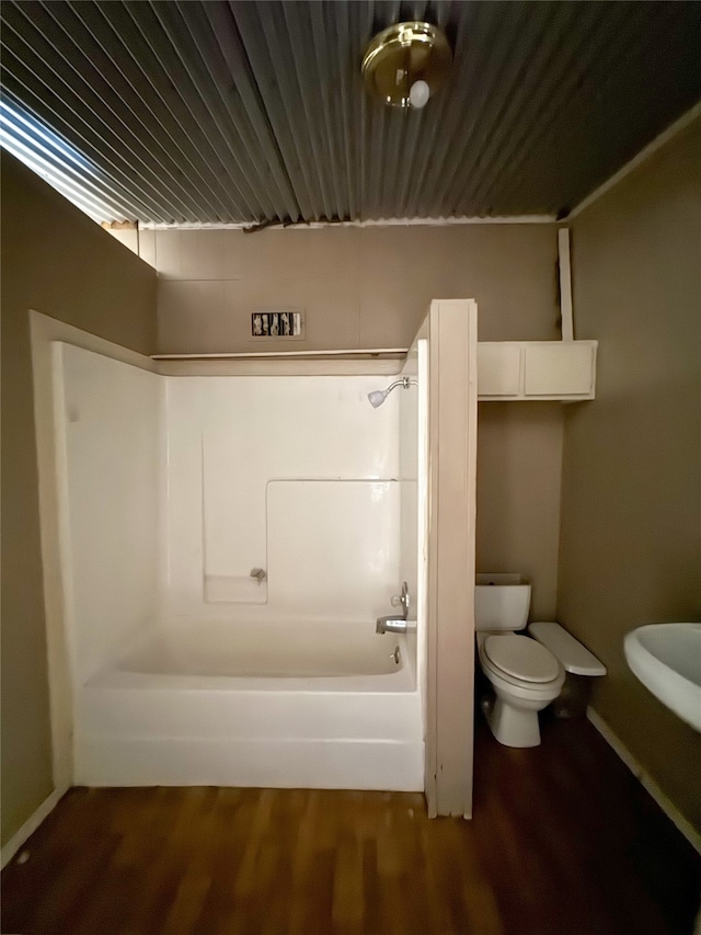 bathroom with shower / tub combination, hardwood / wood-style flooring, and toilet