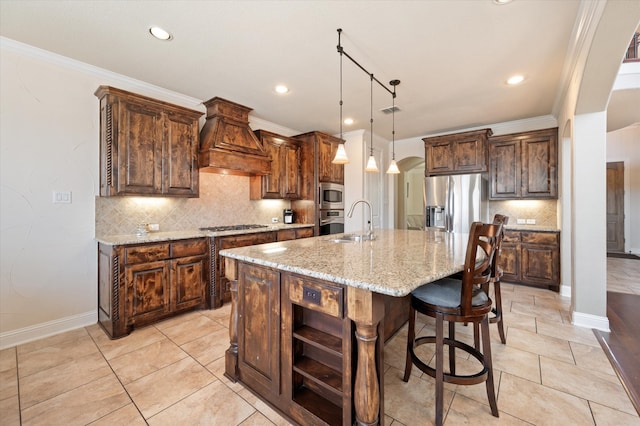 kitchen featuring custom exhaust hood, light stone counters, a kitchen island with sink, pendant lighting, and stainless steel appliances