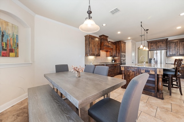 tiled dining room with sink and crown molding