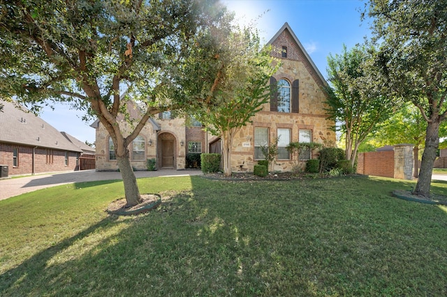 tudor house featuring a front yard and central AC unit