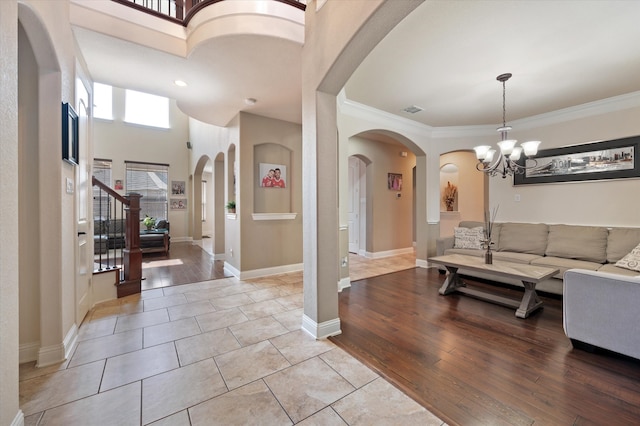 entryway with light hardwood / wood-style flooring, a chandelier, a high ceiling, and crown molding