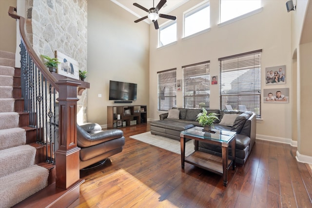 living room with ceiling fan, dark hardwood / wood-style flooring, and a high ceiling