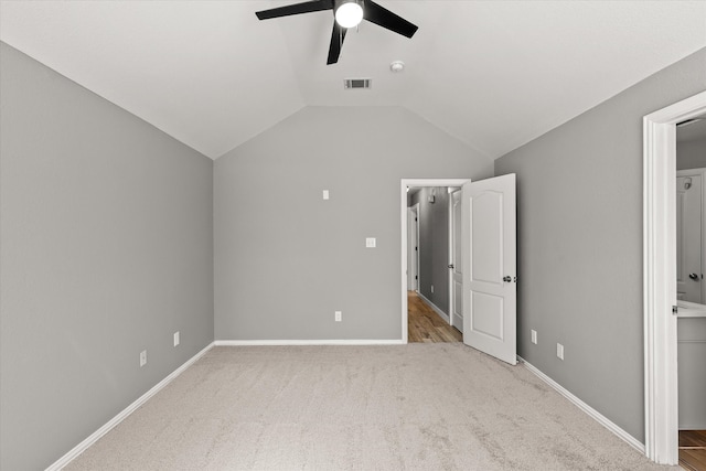 unfurnished bedroom featuring vaulted ceiling, light carpet, ensuite bathroom, and ceiling fan