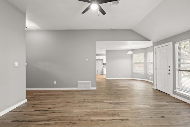 unfurnished living room with hardwood / wood-style floors, a healthy amount of sunlight, and vaulted ceiling