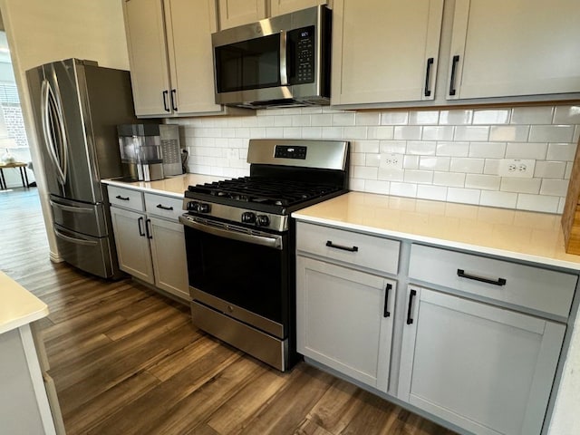 kitchen with tasteful backsplash, appliances with stainless steel finishes, dark hardwood / wood-style floors, and gray cabinets