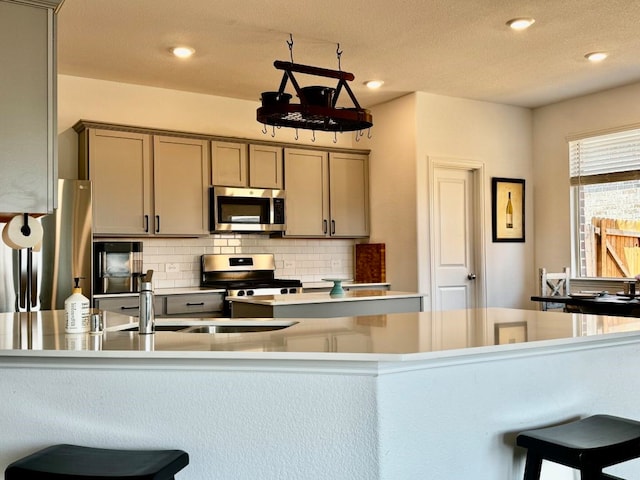 kitchen featuring sink, stainless steel appliances, decorative backsplash, and a textured ceiling