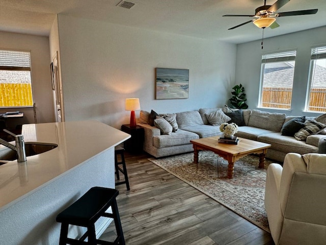 living room featuring ceiling fan, wood-type flooring, and sink