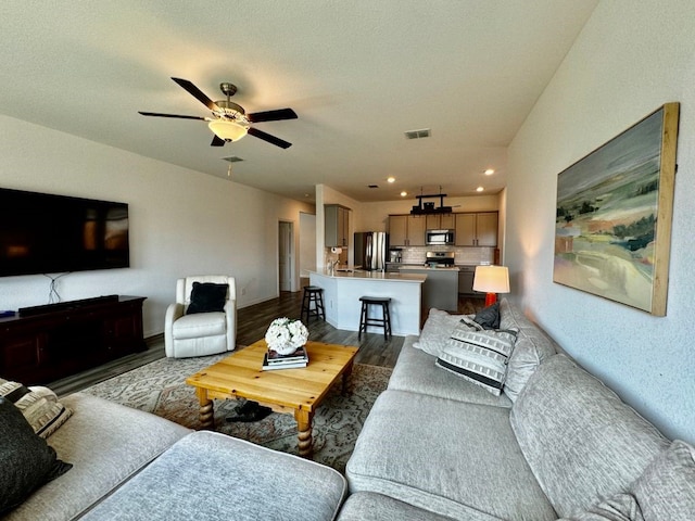 living room with ceiling fan, a textured ceiling, and dark hardwood / wood-style flooring